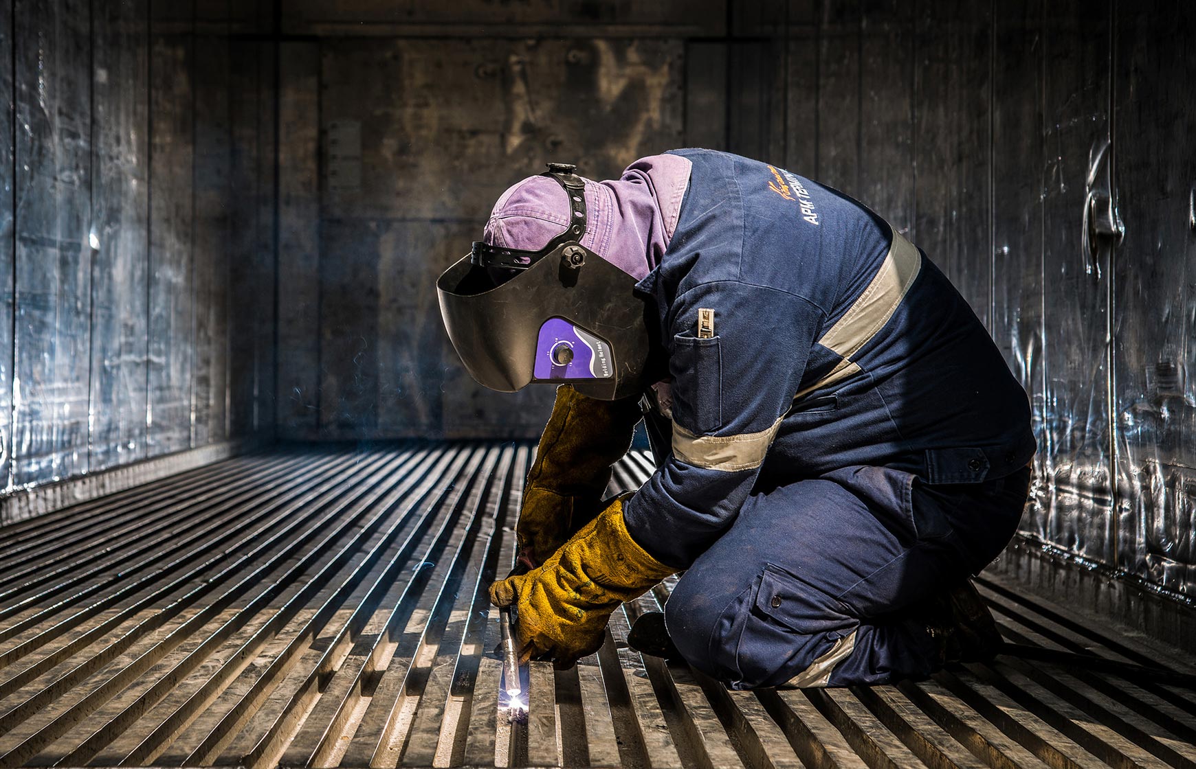 Man making welding repairs on shipping container