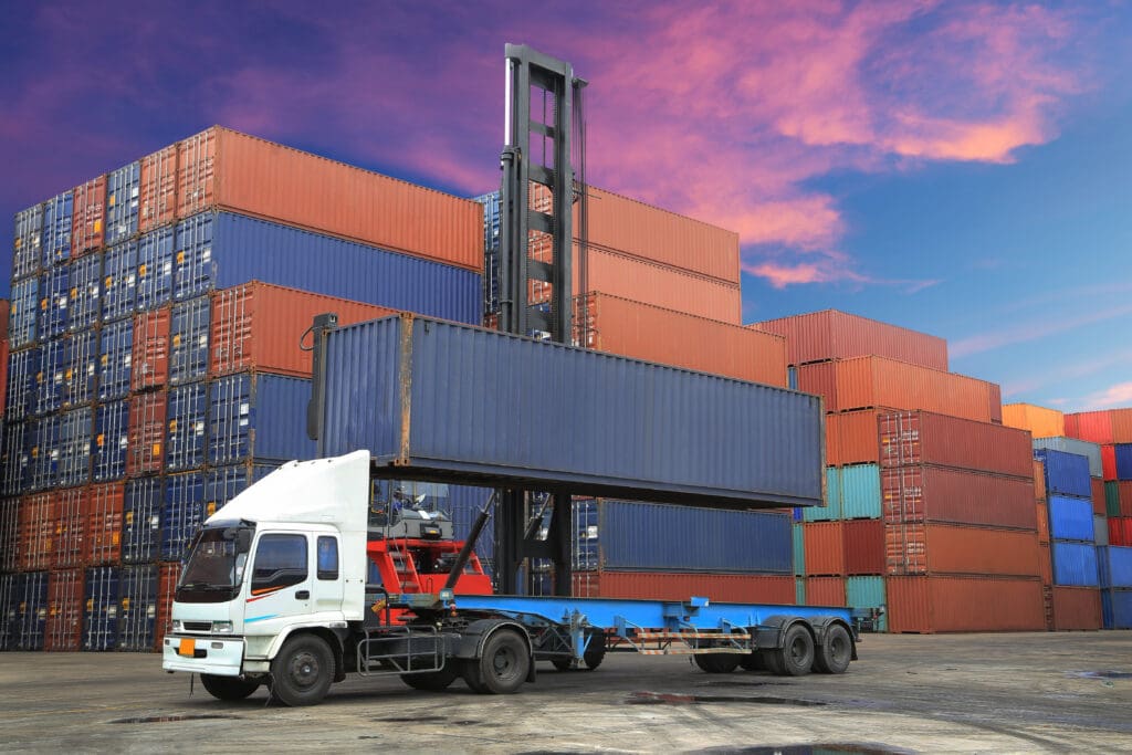 long Beach California. Stack of Freight Containers at the Docks and Depots with Truck being loaded for shipping contaienr delivery at twilight time