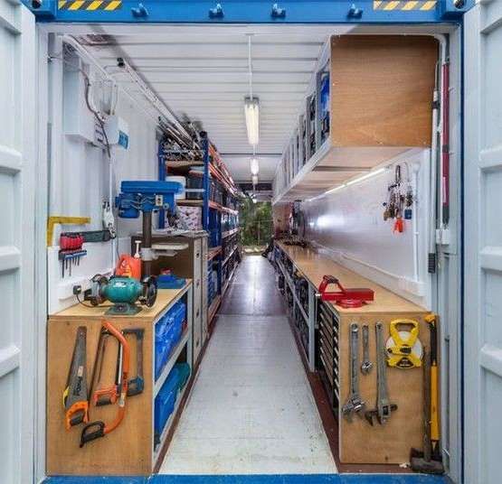 Interior view of a shipping container converted into a fully-equipped mobile workshop with tools and storage.