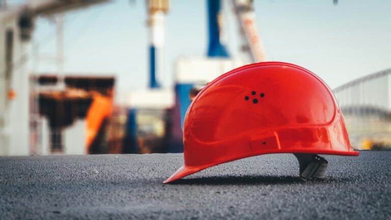 Close up view of a red construction hard hat with construction area in the background.