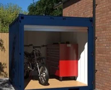 A motorcycle and large mobile tool storage case inside a converted shipping container.