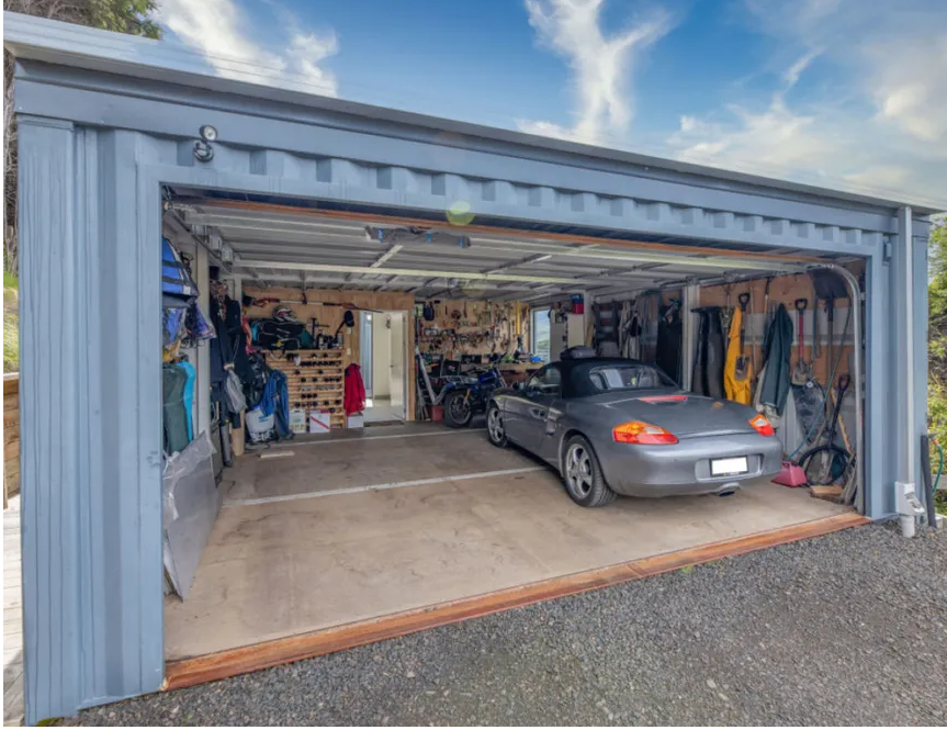 A small car inside a two car garage made from customizing and connecting two shipping containers together.