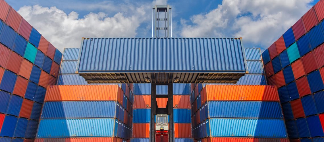 Forklift truck lifting cargo container in shipping yard for transportation import, export and blue sky background