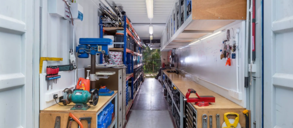 Inside view of a custom designed shipping container workshop, showing workbench space and lots of tool storage.